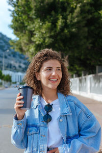 Beautiful young woman with paper cup of coffee take away on the street.