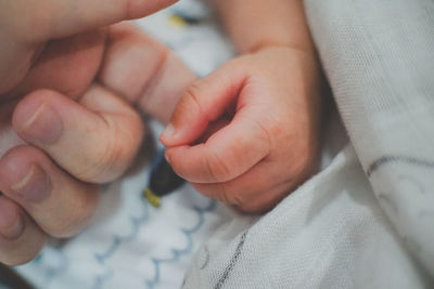 Close-up of mother touching baby on bed