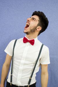 Young man yawning against wall