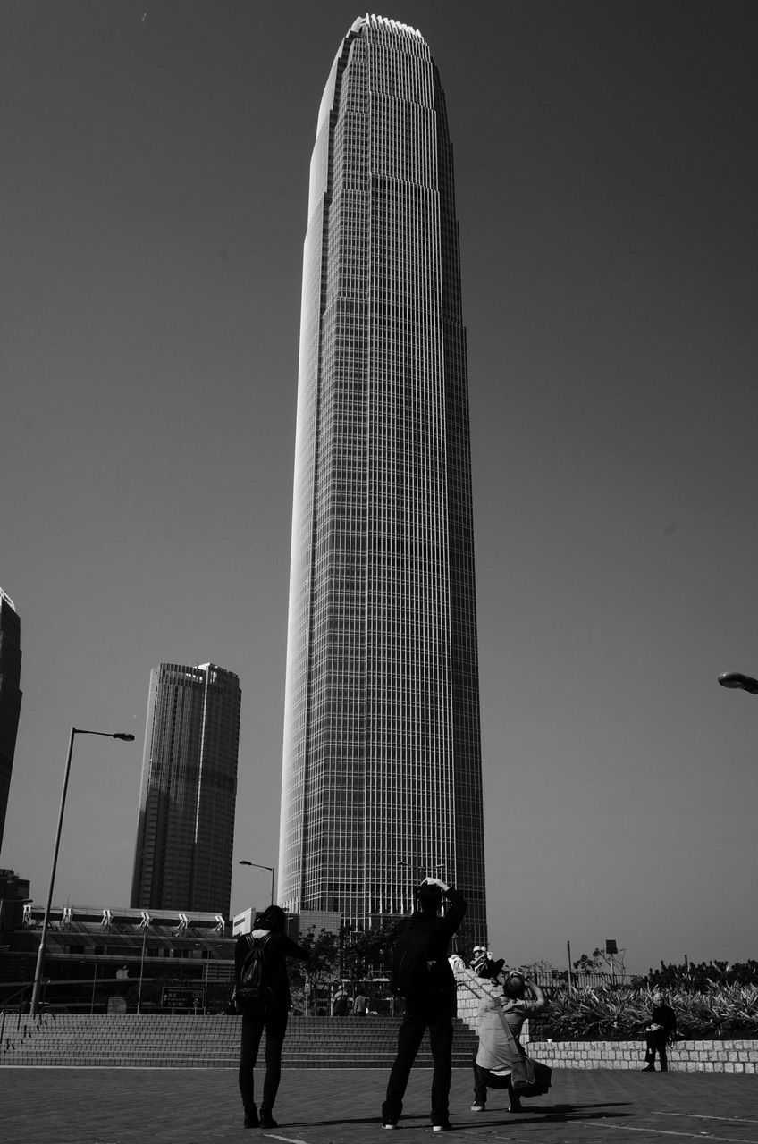 men, built structure, lifestyles, architecture, leisure activity, building exterior, person, clear sky, walking, city, full length, city life, silhouette, low angle view, copy space, bicycle, medium group of people, sky