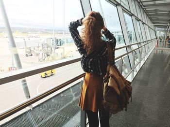 Rear view of girl standing on pedestrian walkway bridge at airport