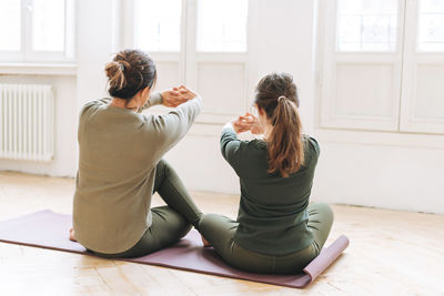 Attractive mother middle age woman and daughter teenager ptactice yoga together in the bright studio