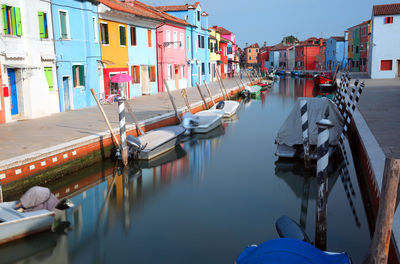 Boats moored in canal amidst buildings in city