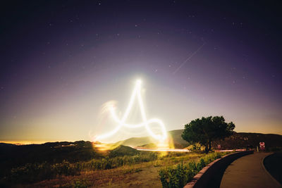 Light trails on road against sky at night