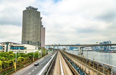 Bridge over road by buildings against sky