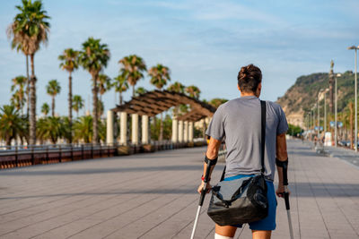 Rear view of man walking on footpath in city