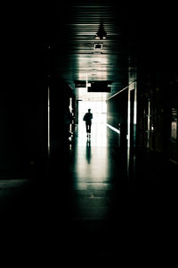 Silhouette man walking in illuminated tunnel
