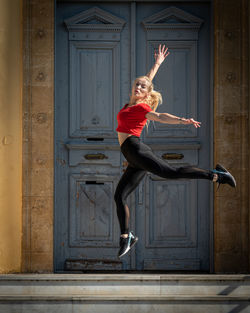 Full length of young woman jumping against wall