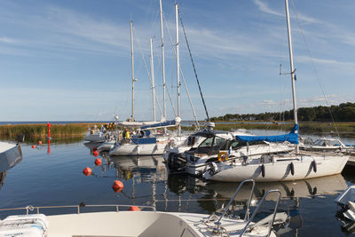 Sailboats moored in sea against sky