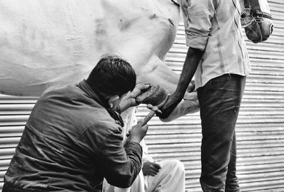 Man attaching shoe on horse