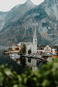 Houses by lake and mountains against sky