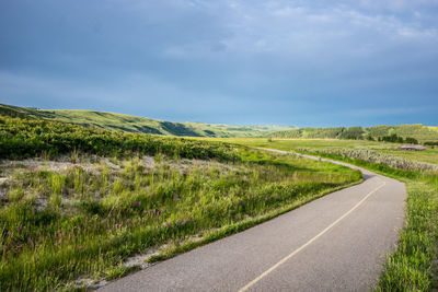 Road amidst field against sky