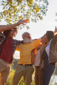 Friends of different ages hugging together in nature against the backdrop of sunset celebrating 