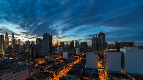 Modern buildings in city against sky during sunset