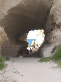 Group of people on rock formation in sea