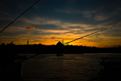 Silhouette bridge over river against sky during sunset