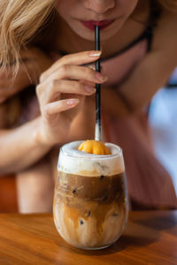 Close-up of woman holding drink served on table