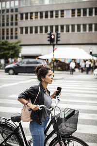 Woman with bicycle on street in city