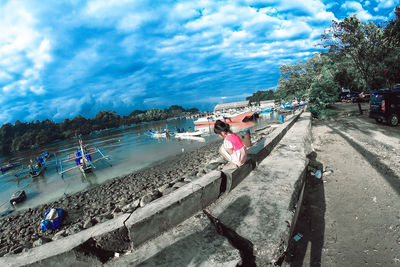 People on beach by city against sky