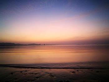 Scenic view of beach against sky at sunset