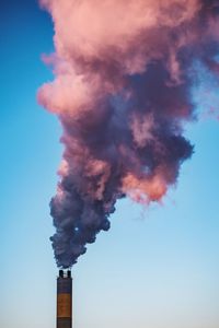 Low angle view of smoke emitting from chimney against clear sky