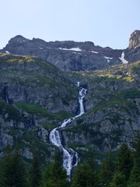 Scenic view of waterfall and mountains against clear sky