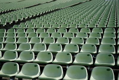 Full frame shot of empty green chairs in stadium