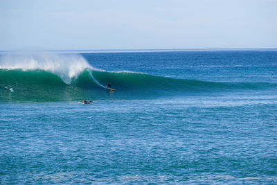 People surfing in sea against sky