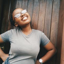 Close-up of smiling young woman standing against wall