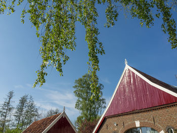 Low angle view of trees and building against sky