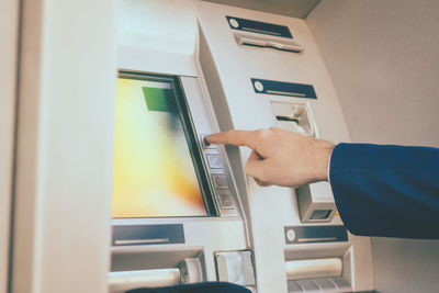 Cropped hand of man using atm machine