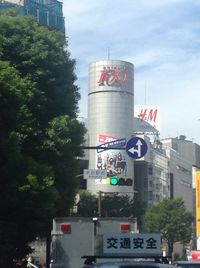 Road sign by building against sky in city