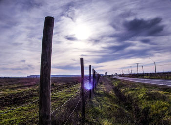 Wooden posts on field against sky