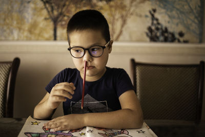 A bored little boy student inserted a pencil into his nose. the concept of adhd