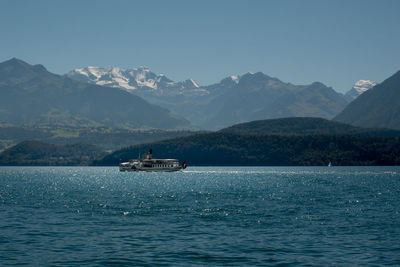 Scenic view of sea and mountains against clear blue sky