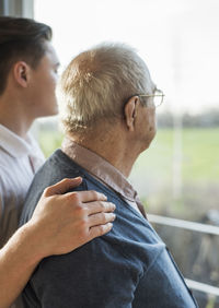 Senior man and his geriatric nurse looking through window