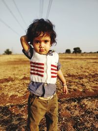 Portrait of cute baby girl standing on field against sky