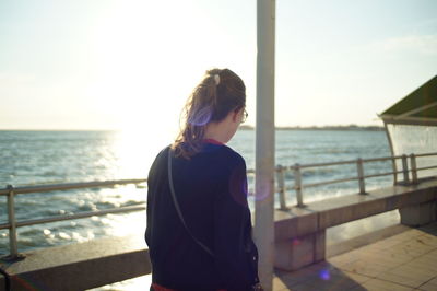 Rear view of woman overlooking calm sea