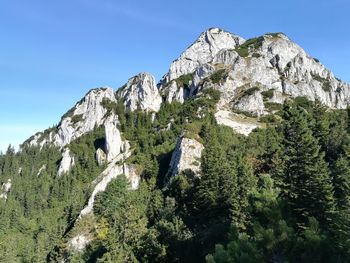 Low angle view of rocky mountains against blue sky