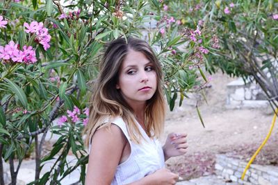 Beautiful woman standing by pink flowering trees