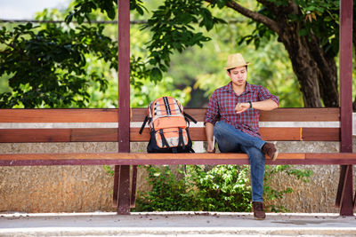 Tourist with backpack sitting on bench at bus stop