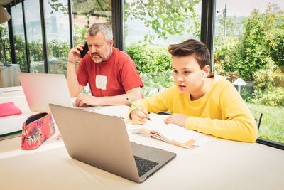 Father working while son studying at home