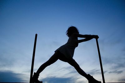 Low angle view of silhouette woman jumping against sky