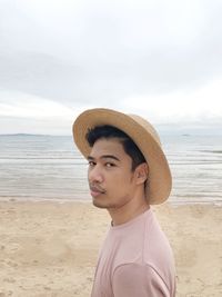 Portrait of man wearing hat on beach against sky