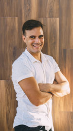 Portrait of smiling man standing against wooden wall