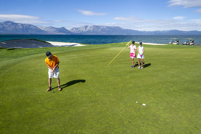 Three people playing golf at edgewood tahoe in stateline, nevada.