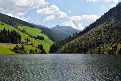 Scenic view of river by mountains against sky