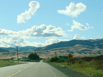Road by mountains against sky
