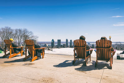 Rear view of people on chair against sky