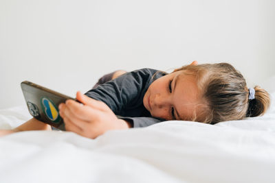 Young woman using mobile phone while lying on bed at home